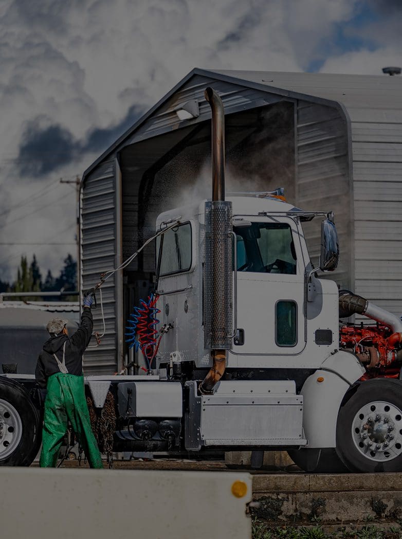 A man in green overalls standing next to a white truck.
