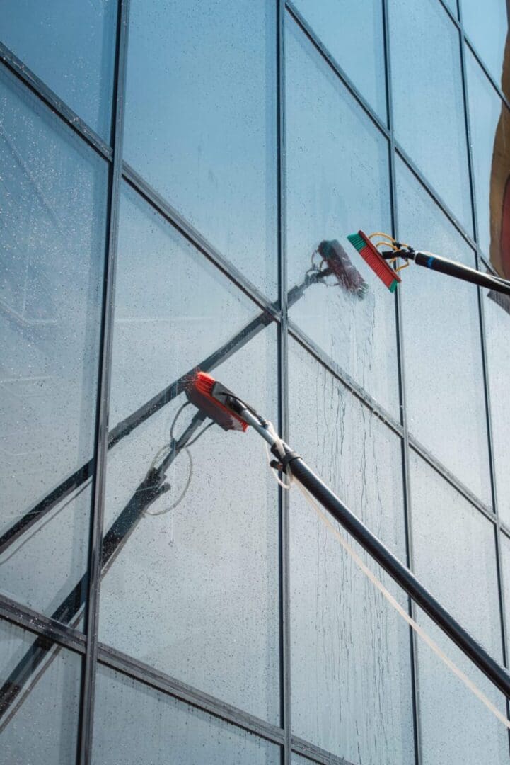 Window cleaning with long brushes on building.