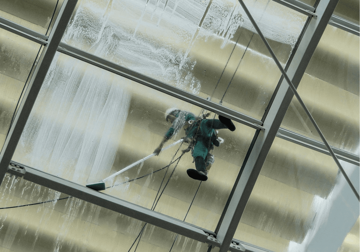 Person cleaning large glass window, suspended mid-air.