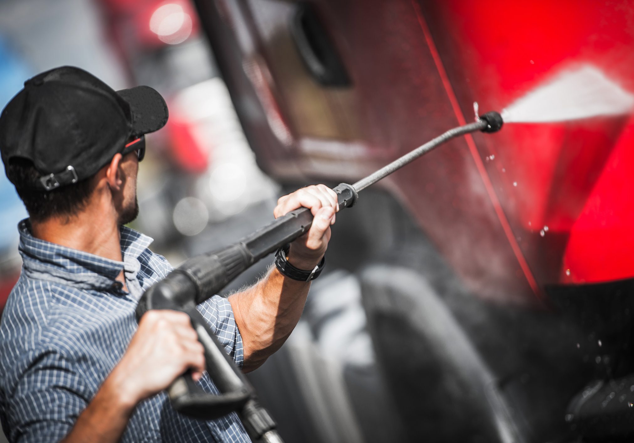 Close-Up Of Man Washing Truck In Garage A man is using an electric power washer.