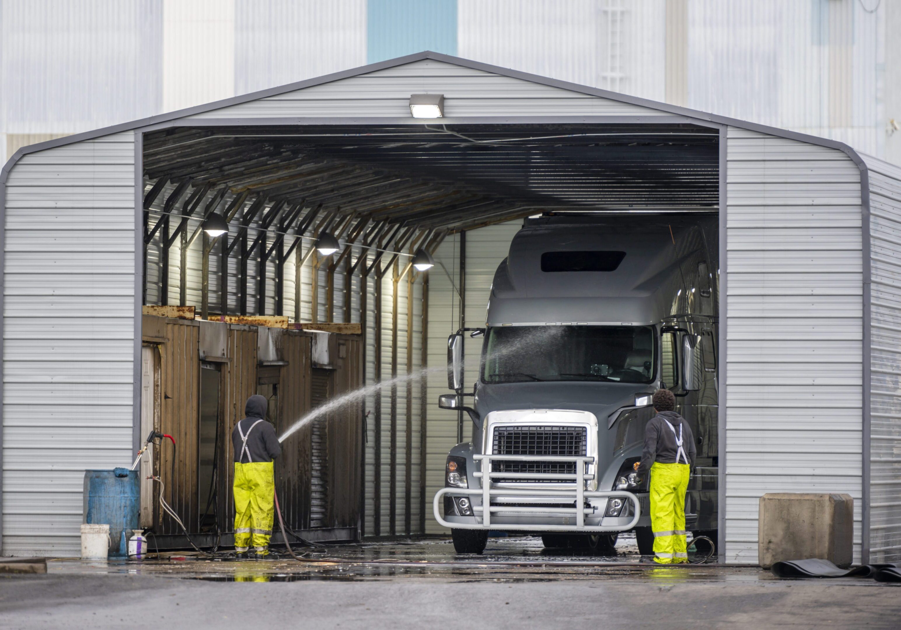 Big rig semi truck washes in covered car wash station with manual washing Truck being washed in a large garage.