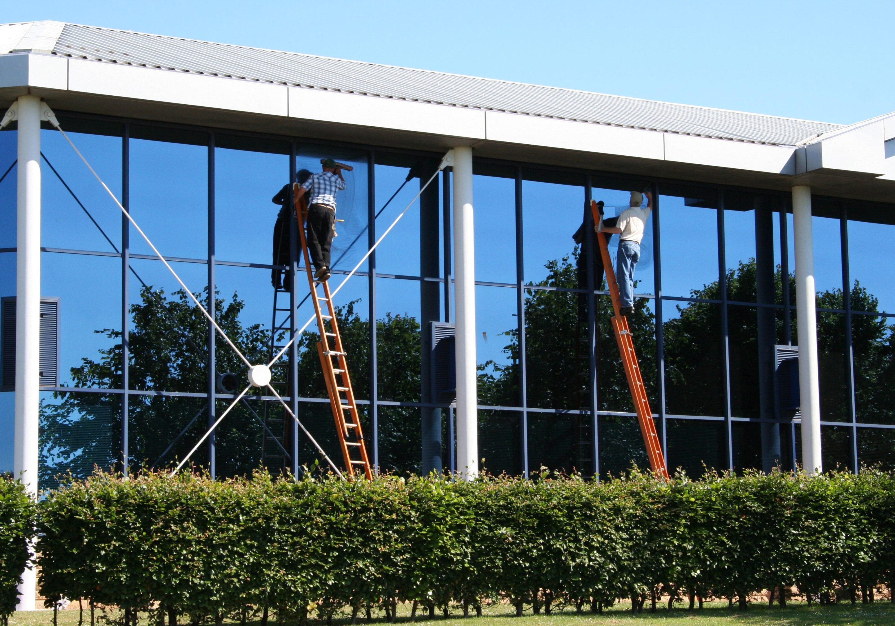 Two window cleaners at work Three men on ladders working on a building.