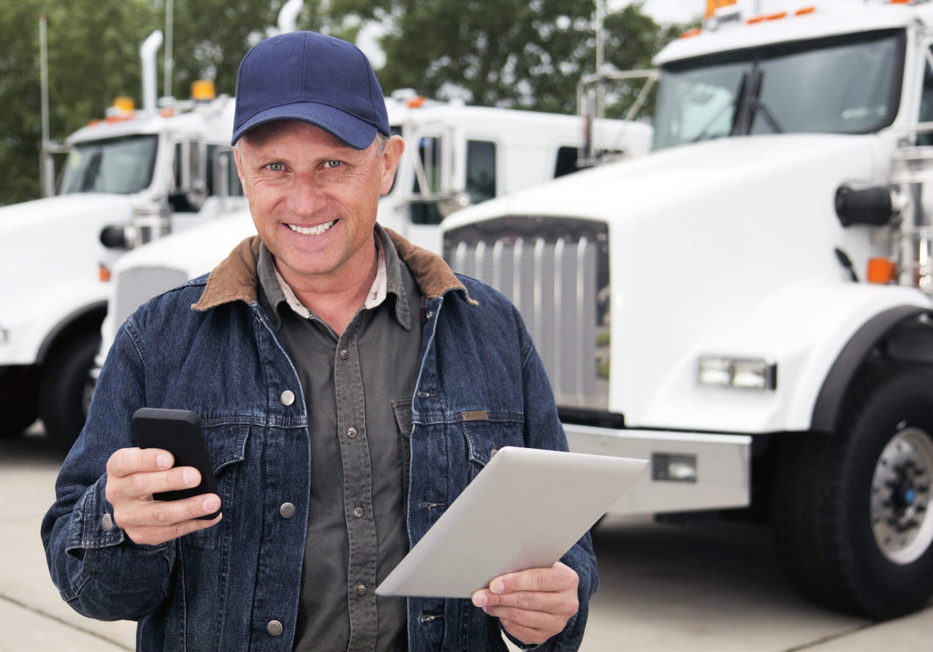 Truck Driver and Technology Man with tablet and phone near trucks.