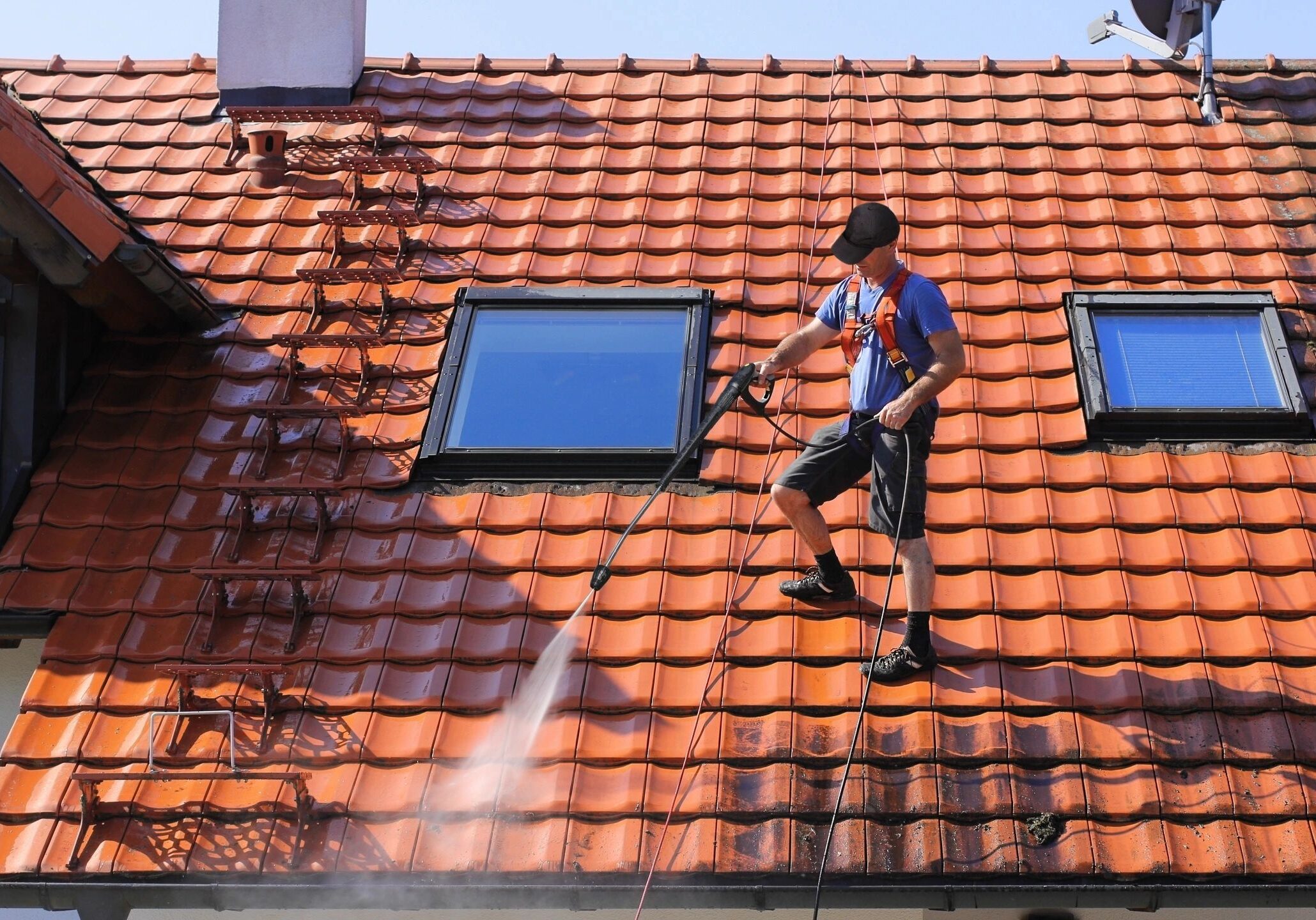 A person is pressure washing a roof.